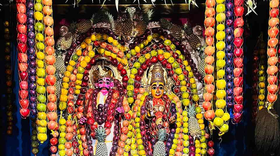 Sri Tirupatamma Ammavari idols decorated with colorful fruit garlands and traditional ornaments during a special ritual at Penuganchiprolu Temple.