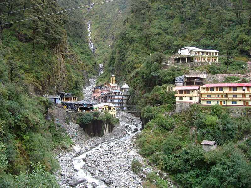 Scenic landscape of Yamunotri with mountain stream, temples, and houses nestled in the Garhwal Himalayas