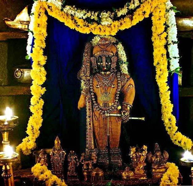 Decorated idol of Lord Krishna at Udupi Sri Krishna Temple with floral garlands and lamps