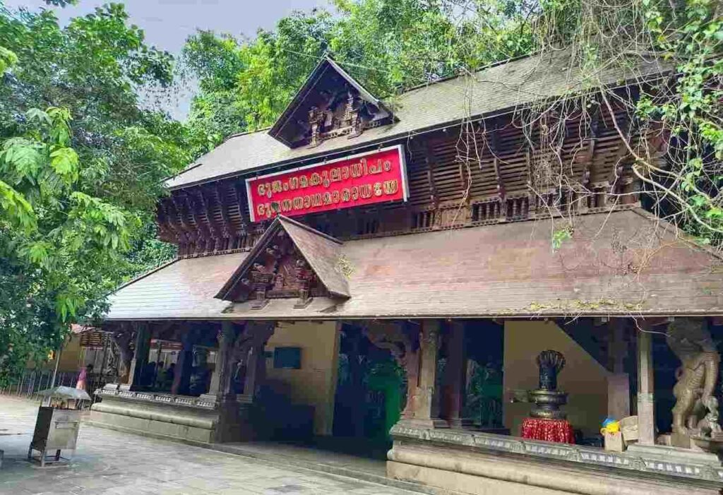Traditional Kerala-style architecture of Mannarasala Sree Nagaraja Temple surrounded by forest