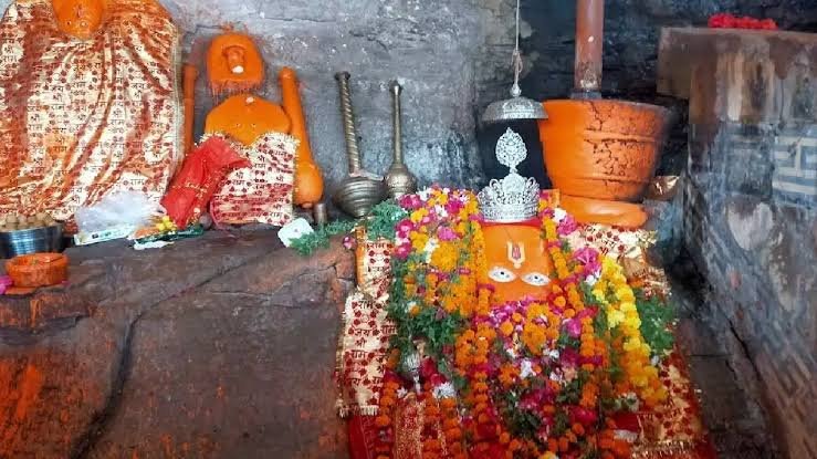 Hanuman Dhara Temple in Chitrakoot featuring the sacred Hanuman idol adorned with flowers and offerings inside the ancient cave shrine.