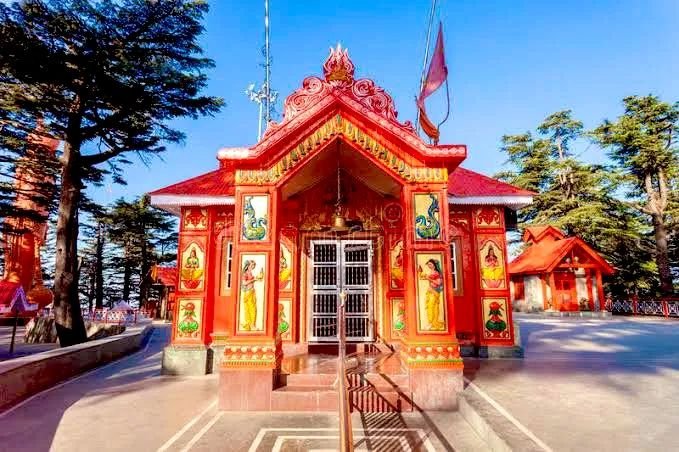 Jakhu Hanuman Temple in Shimla surrounded by cedar forests and Himalayan landscapes under a clear blue sky.