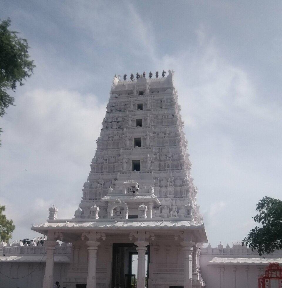 White Rajagopuram of Karmanghat Hanuman Temple Hyderabad standing tall against the blue sky.