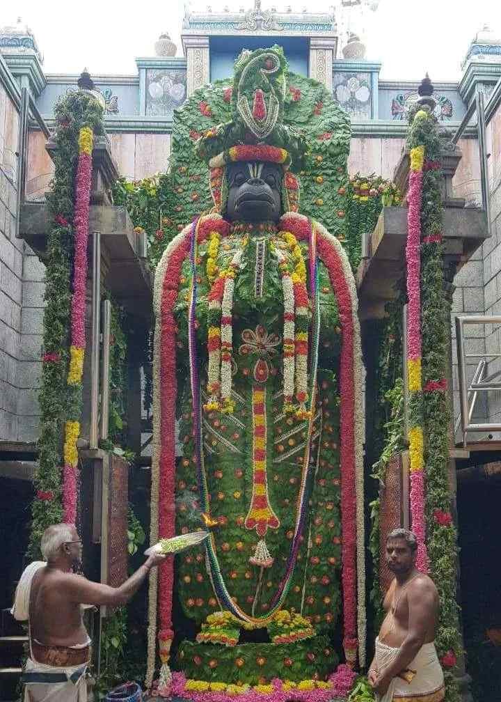 Lord Namakkal Anjaneyar adorned with colorful flower garlands during a special festival celebration.